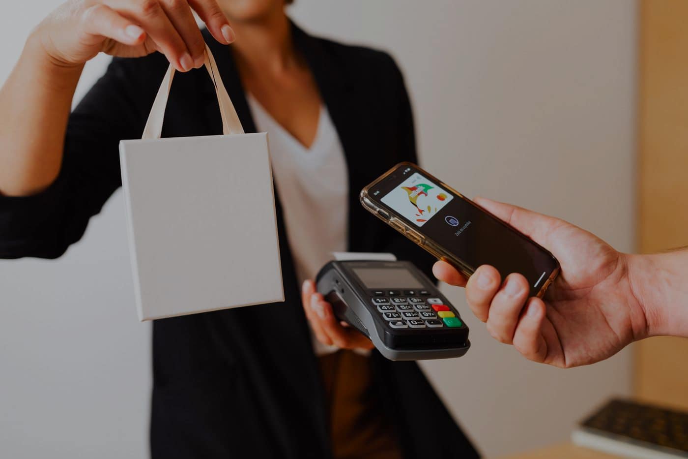 A shopper paying with their phone at a counter and being handed the bag.